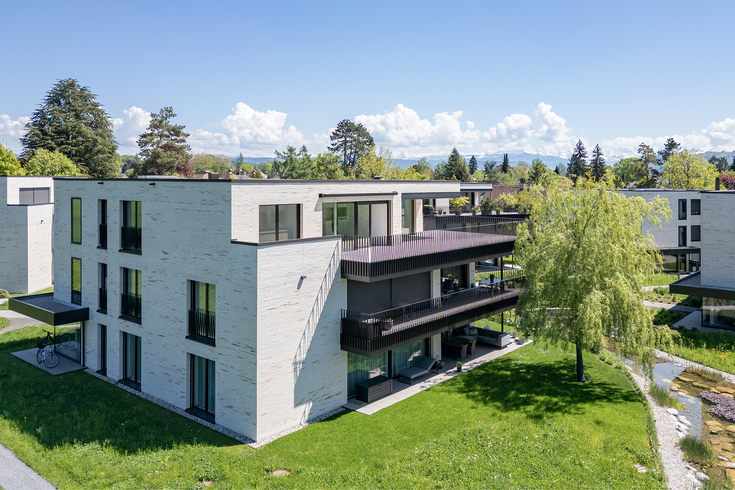 Blick auf das Haus mit drei Parteien in Muri bei Bern. Die zu verkaufende Attikawohnung liegt direkt neben der Landwirtschaftszone und man sieht bis in die Berge des Berner Oberlands.