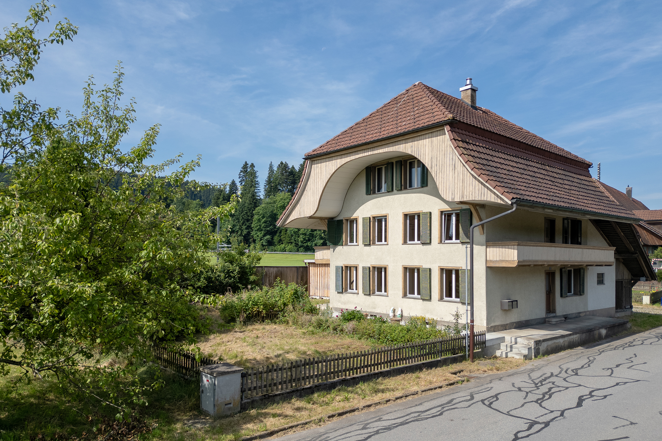 Drohnenfoto von einem kleinen Bauernhaus mit zwei Wohnungen und einem Krüppelwalmdach.
