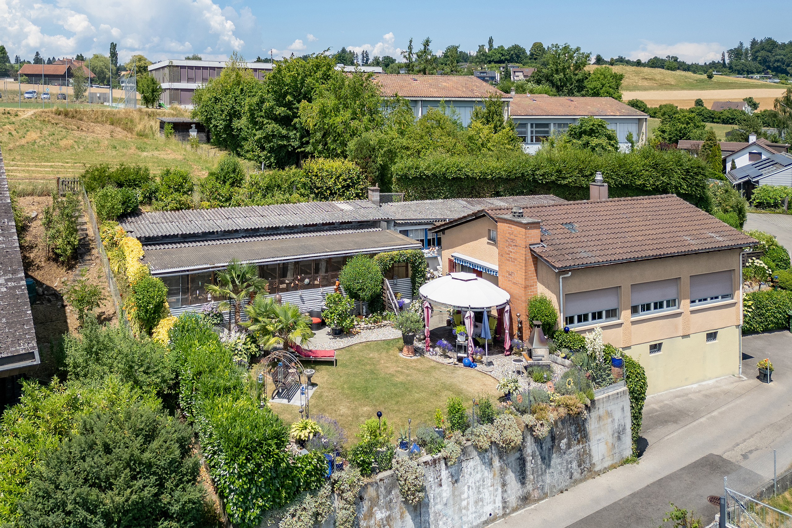 Sicht auf den Garten, das Haus und die Volieren des zu verkaufenden Grundstücks in Herrenschwanden.