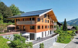 Ferienwohnung in Zweisimmen Aussenansicht des Vollholzhauses in Zweisimmen. Die Verkleidung besteht aus einheimischen Fichtenholzschindeln. Die vollintegrierte Solaranlage auf der gesamten Dachfläche liefert mehr Strom als genutzt wird.