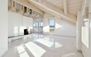 Dachwohnung in Belp Blick in das helle Wohnzimmer mit Kamin, Sichtbalken vom Dachstuhl und Blick zum Flughafen Belp.