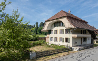 Mehrfamilienhaus in Bowil Drohnenfoto von einem kleinen Bauernhaus mit zwei Wohnungen und einem Krüppelwalmdach.