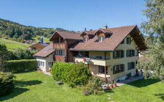 Mehrfamilienhaus in Wattenwil Blick auf ein Mehrfamilienhaus mit grossem Umschwung und fünf Wohnungen. Im Hintergrund steht das Gantrischgebirge.